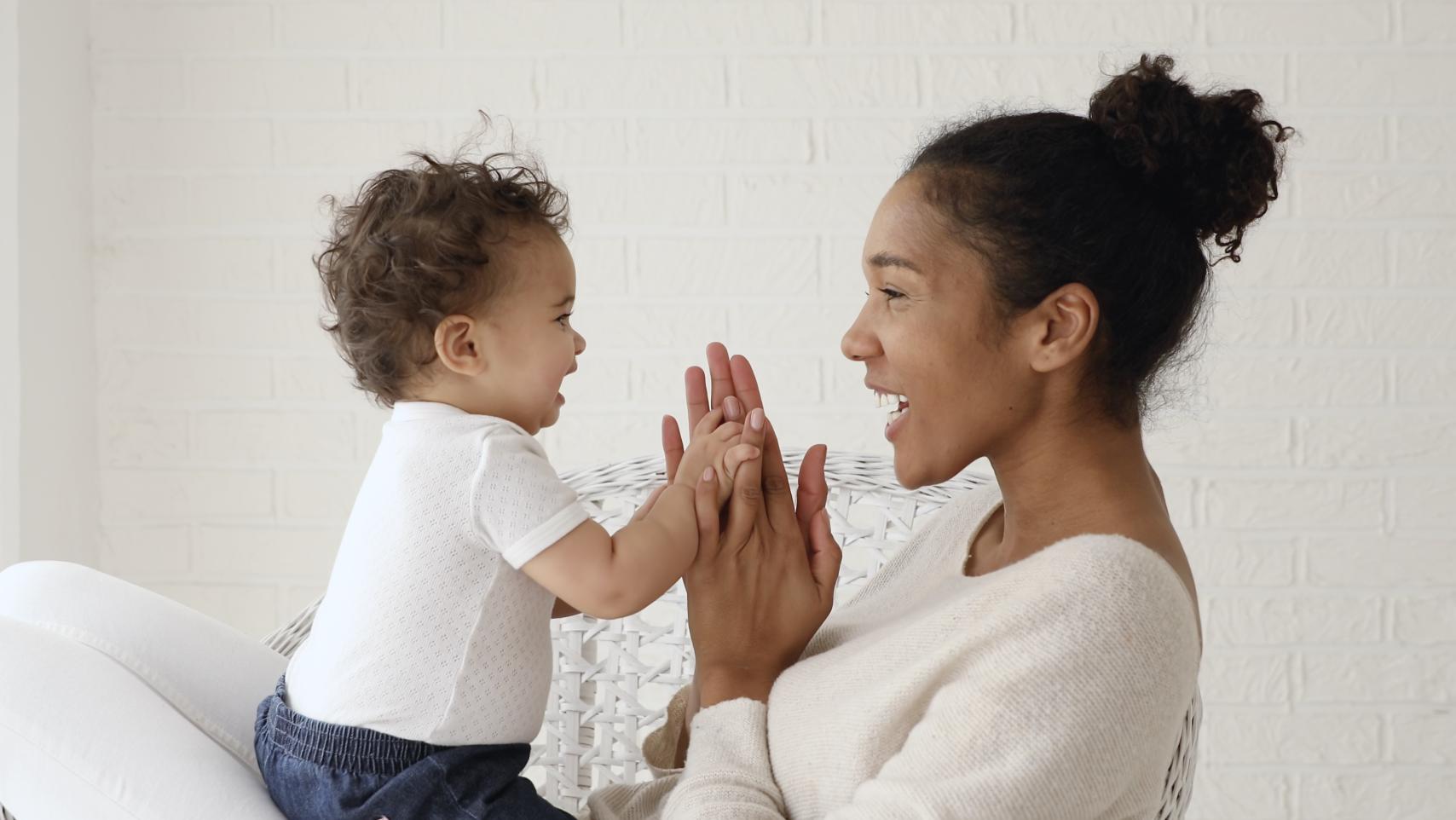 A baby and mother face each other, laughing