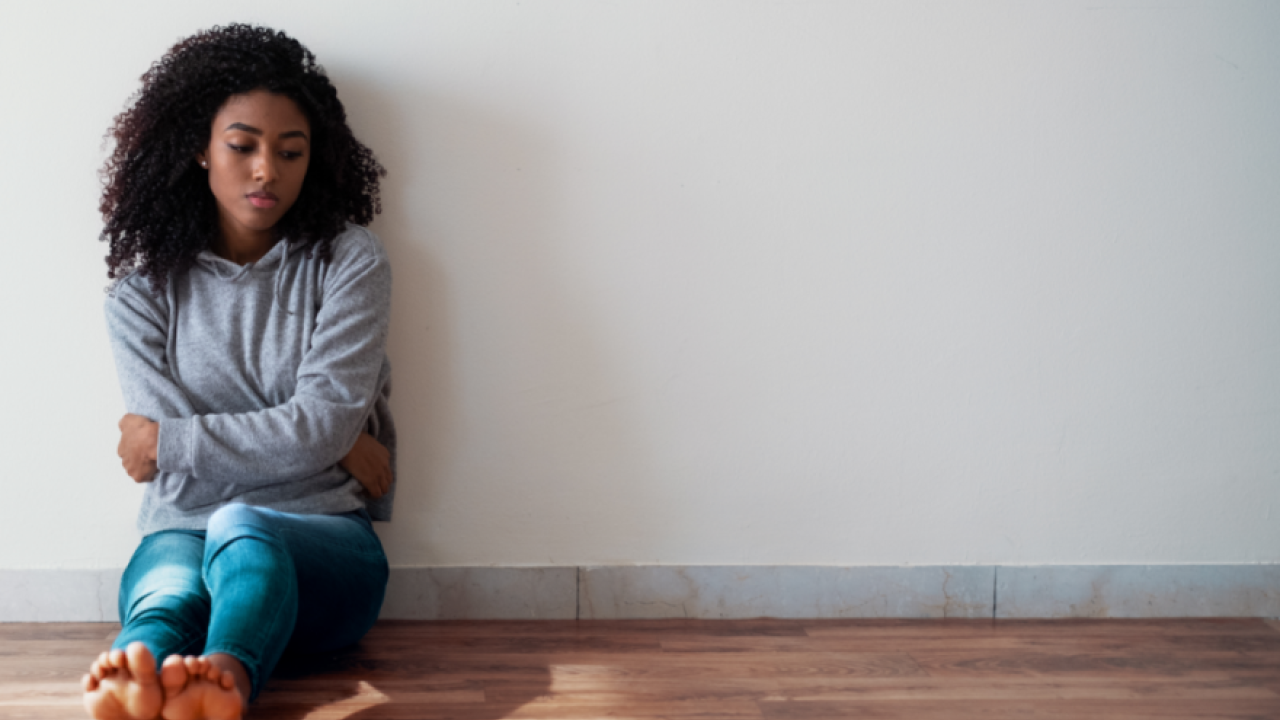 A sad, young woman sitting on the ground